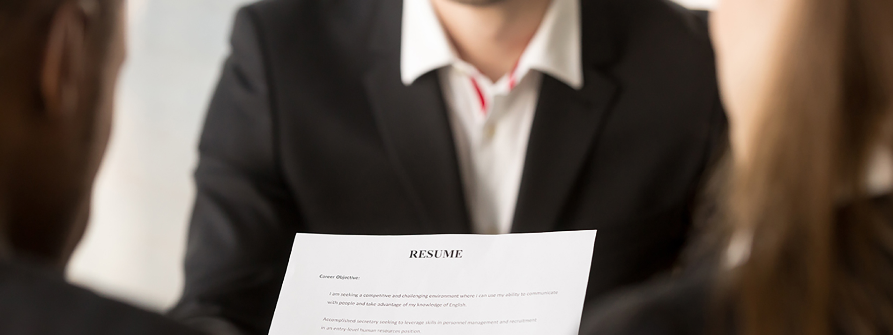 Man holding up a resume and interviewing a woman