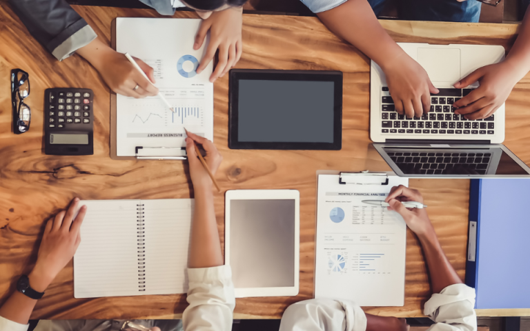Office workers at a large table with papers