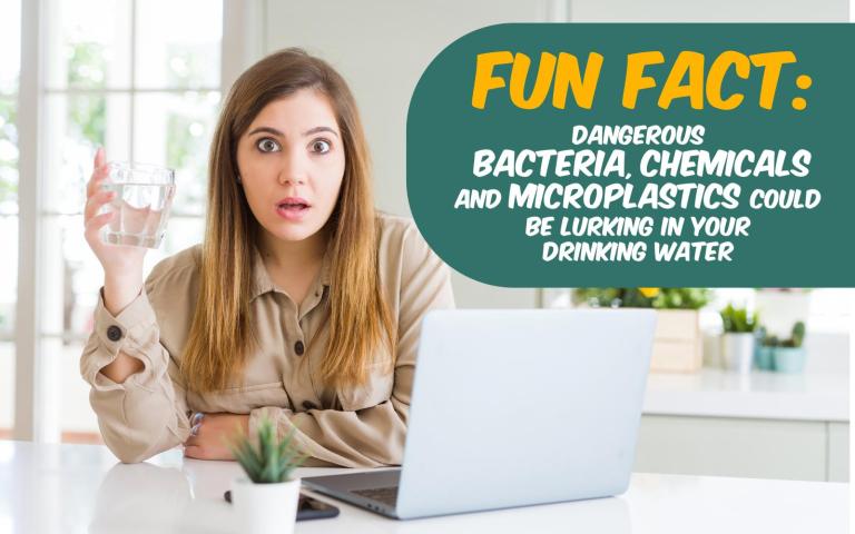 woman looking surprised holding a glass of water behind laptop