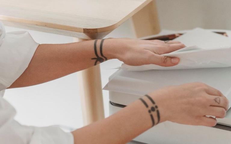 person touching printed documents on top of a printer