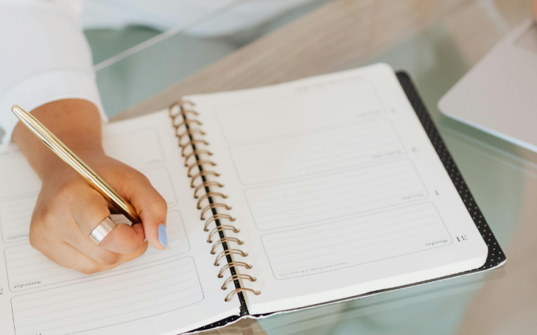 person writing on paper and computer