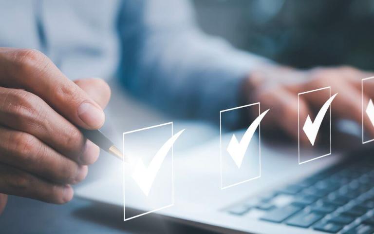 businessperson checking boxes above laptop