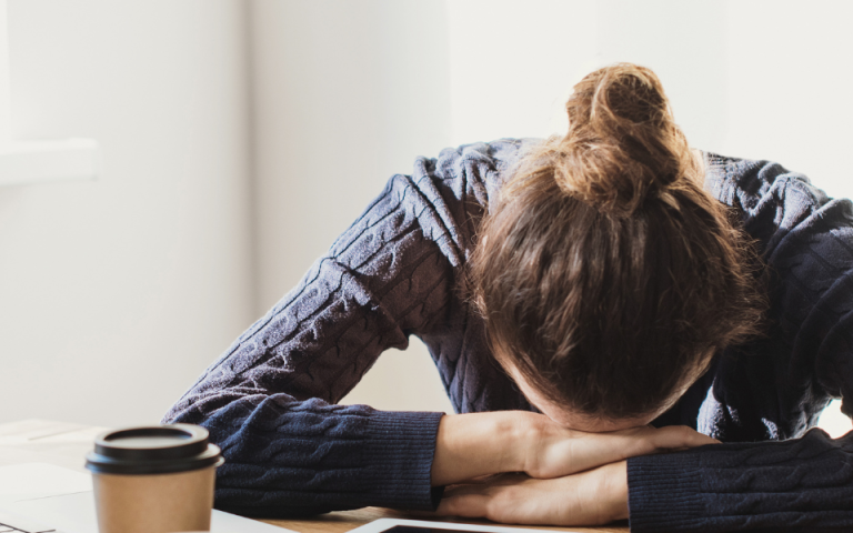 woman surrounded by tech with head on table