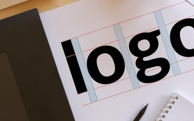 mock-up of logo next to scissors, laptop