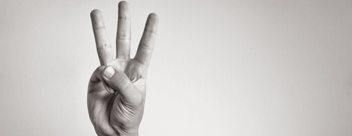 Black and white photo of a hand gesturing number 3 on blank background