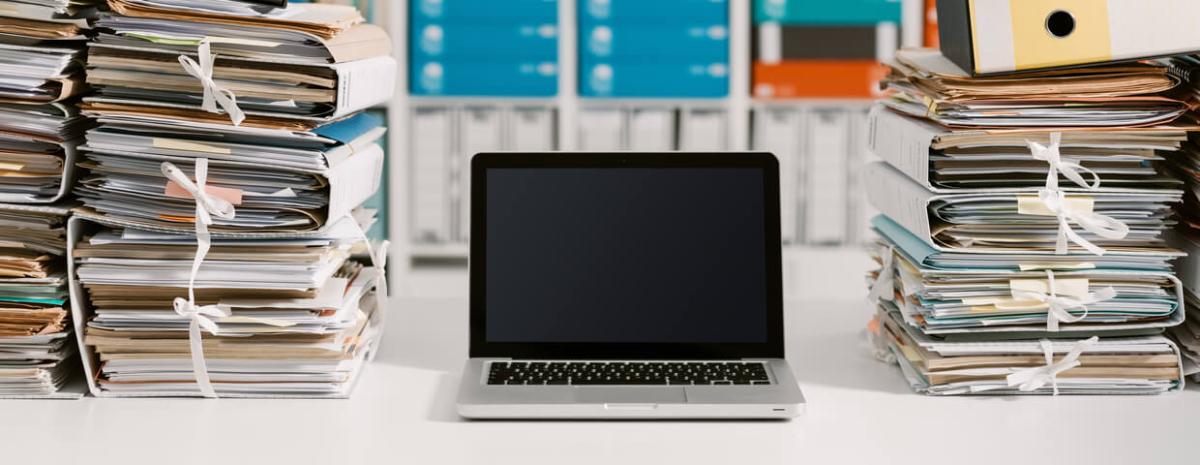 Laptop on desk full of documents 