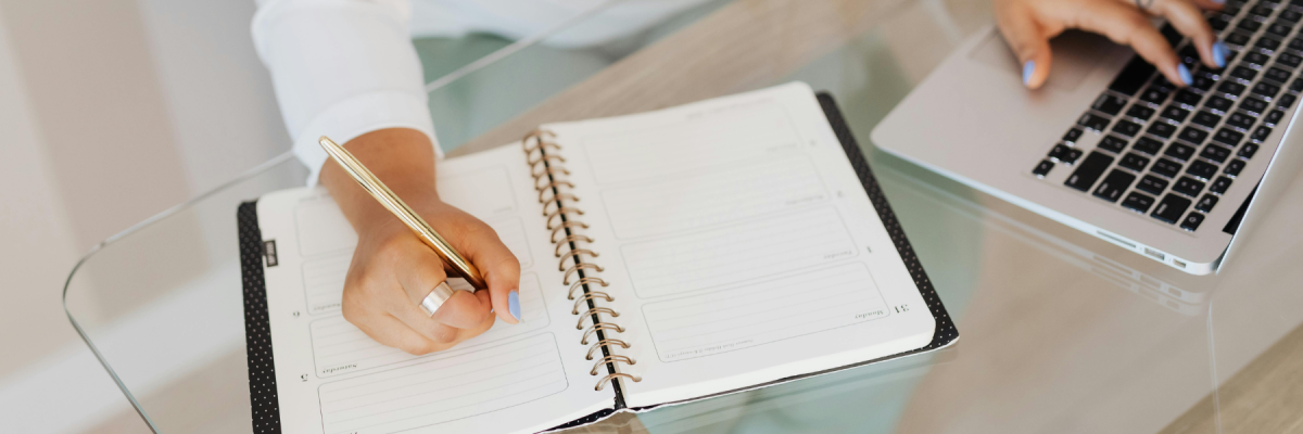 person writing on paper and computer