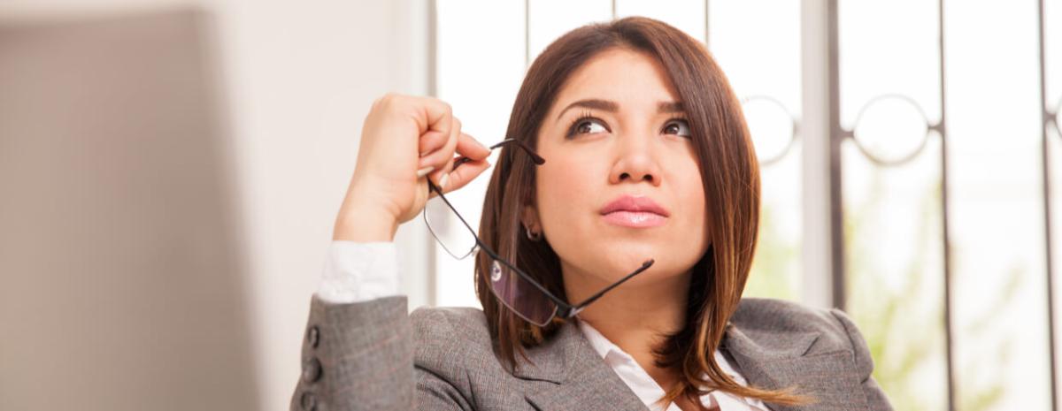 Business woman thinking while holding glasses up to face.