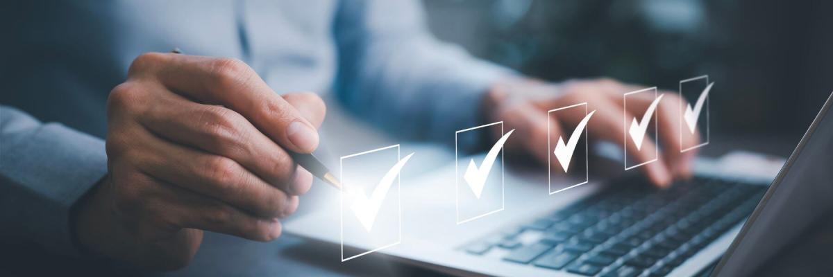 businessperson checking boxes above laptop