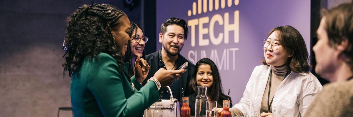 Event attendees at a table networking, signage behind them