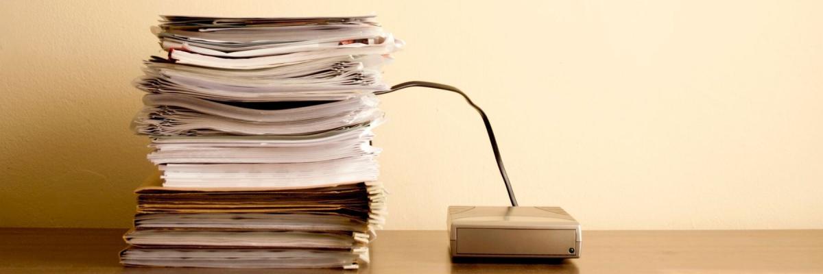 stack of papers with a wire attached to external hard drive