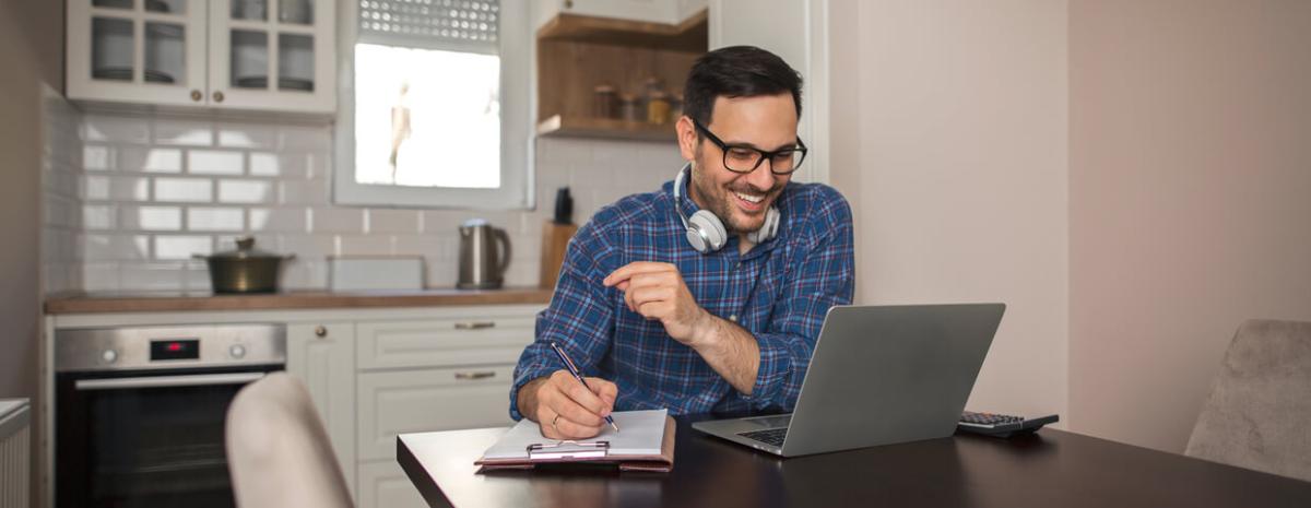 Man working remotely at home, using laptop, wearing headphones