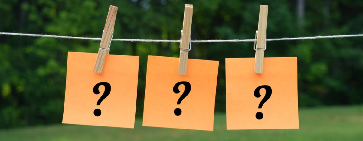 Three orange pieces of paper with one black questions mark on them being hung on a clothes line.